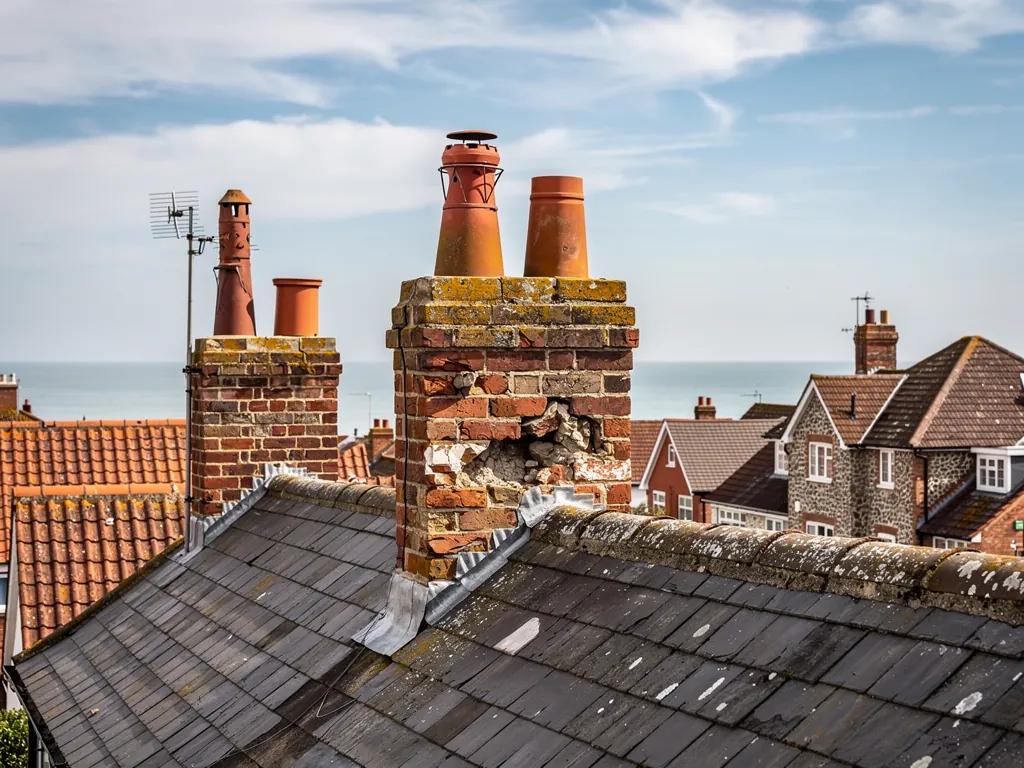 Terrace chimney stacks with spalled bricks above a slate roof