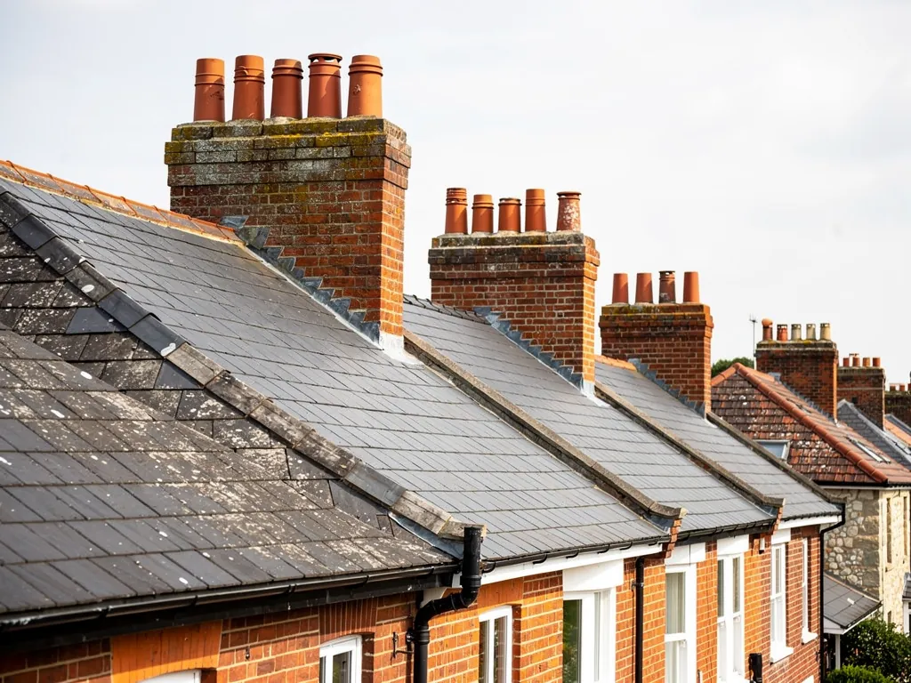 Tall brick chimney stacks with clay pots rising from the slate roofs of a Victorian terrace