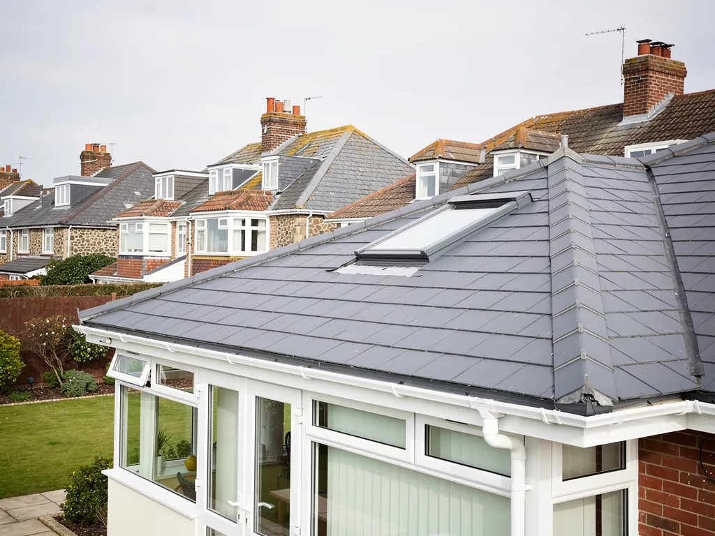 The rear of a chalet bungalow with a conservatory under a new solid tiled roof