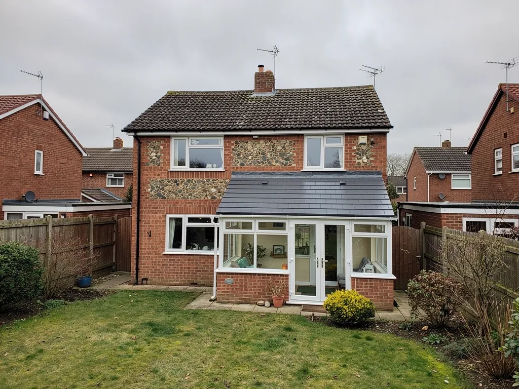 A brick and flint house with a new solid tiled conservatory roof