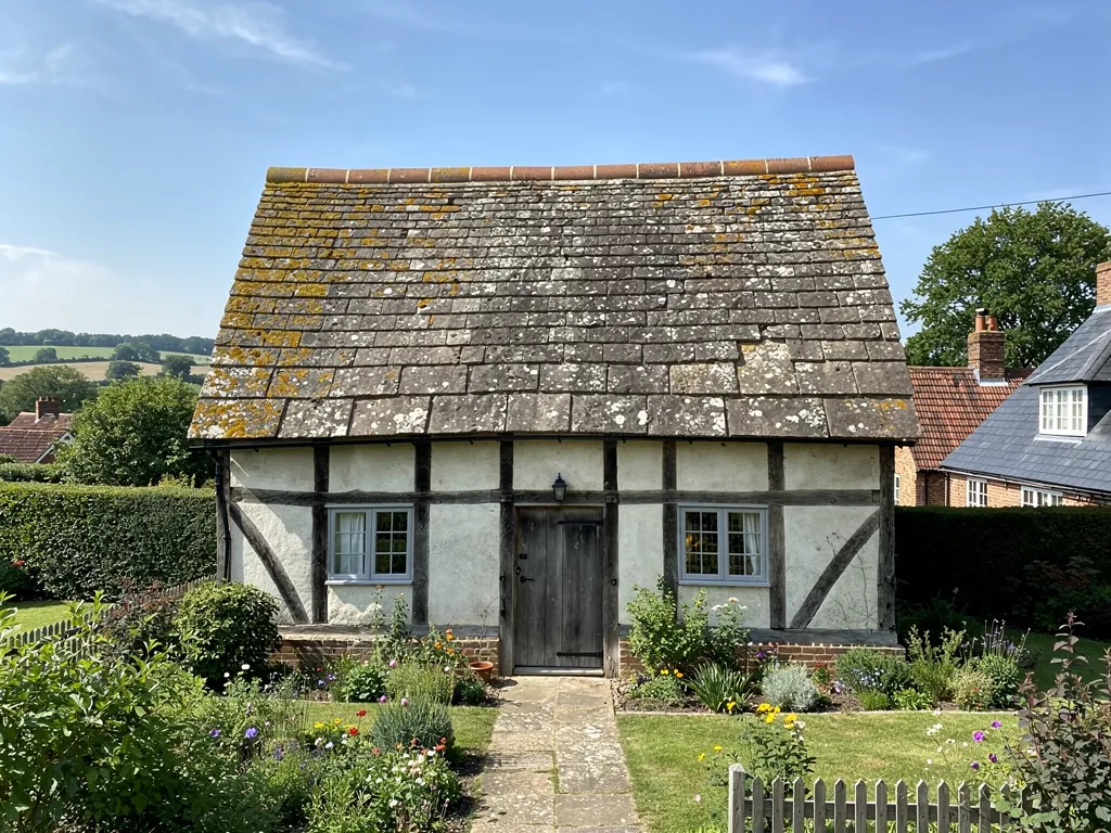 A timber-framed cottage with a heavy Horsham stone roof