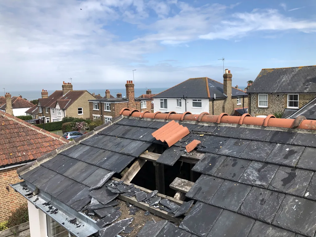 Broken ridge tiles and slipped slates on a terrace roof after a storm